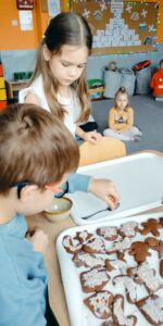 Dziewczynka i chłopiec ozdabiają pierniki