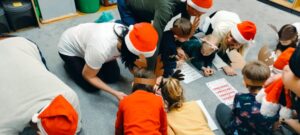 rodzice i dzieci wypełniają na dywanie kartę pracy