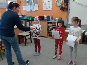 trzy dziewczynki odbierają dyplom od nauczycielki