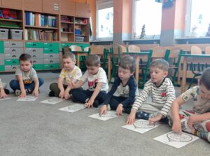 dzieci siedzą na dywanie, przed nimi obrazek bombki