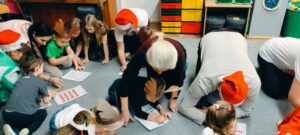 rodzice i dzieci wypełniają na dywanie kartę pracy