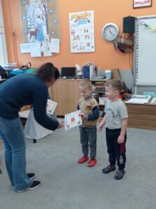 nauczycielka wręcza dyplomy chłopcom