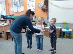 nauczycielka wręcza dzieciom dyplomy