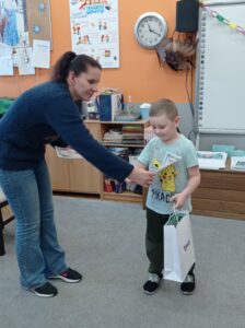 nauczycielka wręcza dyplom chłopcu