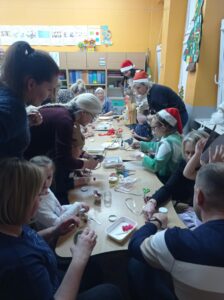 grupa rodziców i dzieci siedzi przy stolikach